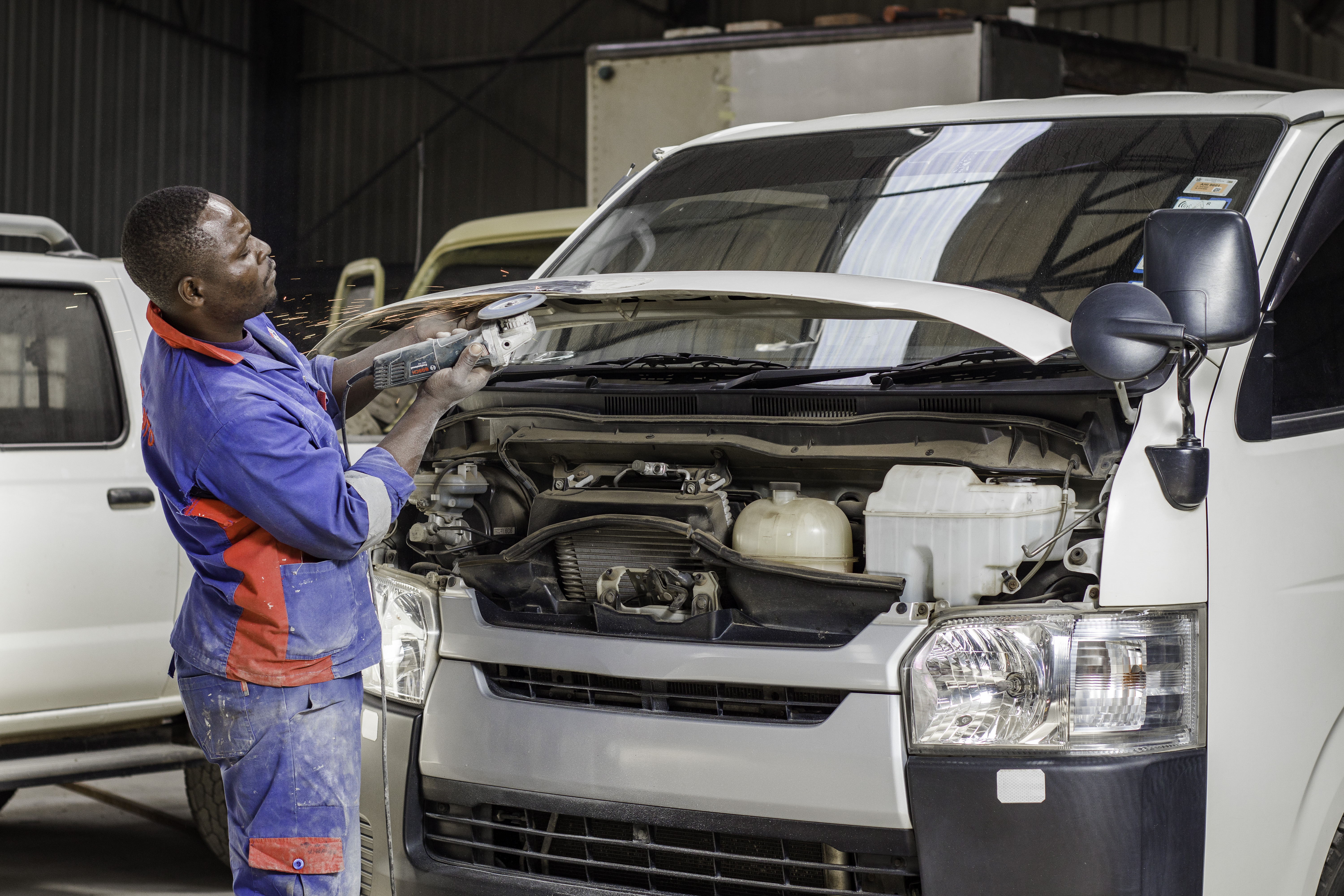 Grand Auto Premier technician grinding a vehicle panel